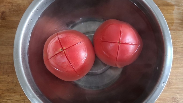 金针菇番茄龙利鱼,2个大番茄顶部划十字，顶部朝下放进碗中浇开水烫2-3分钟后剥去皮。