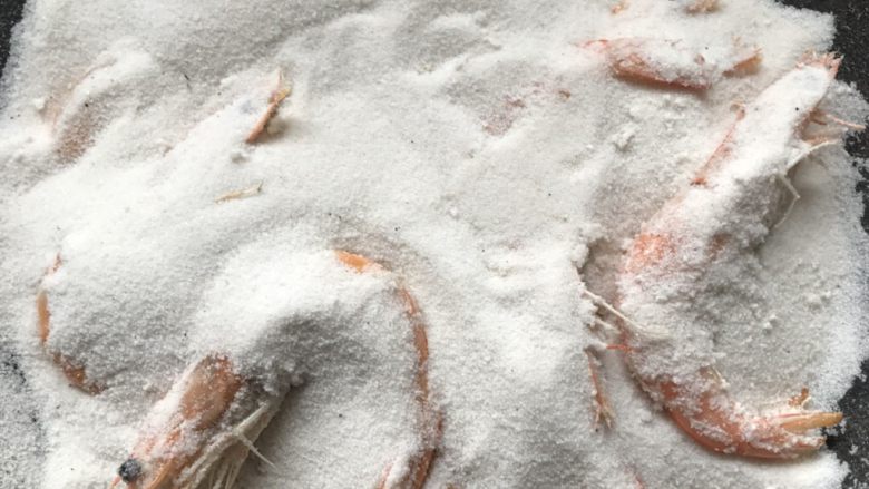 盐焗虾,待盐炒至高温后，将虾放入其中，并用盐完全覆盖虾，将火调小，盖上锅盖盐焗4分钟。