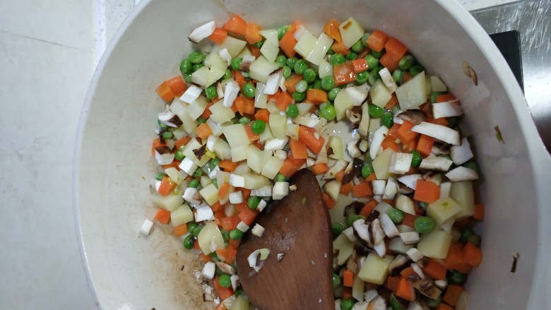 云腿煲仔饭,少油依次加入土豆，胡萝卜，豌豆，蘑菇炒香备用
