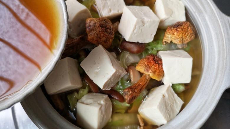 白菜豆腐煲,将炒过的白菜移入砂锅中，将焯过水的豆腐滑入砂锅，加入泡发菌菇的水。加盖炖煮。