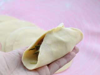 猪肉萝卜丝玉米面蒸饺,取一张饼皮用左手托住，在中间放适量馅料，然后将饼皮的中间对折捏严