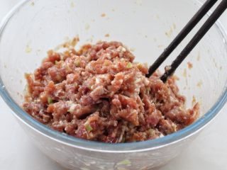 猪肉萝卜丝玉米面蒸饺,然后用筷子顺时针一个方向搅拌至肉馅上劲儿，这一步是为了使馅料抱团不散开，口感更好