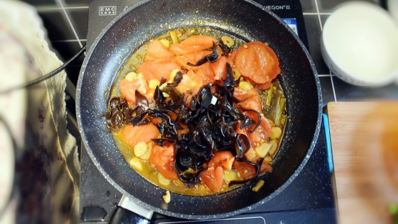 番茄炒包菜盖浇饭,西红柿变软，汤汁炒出后，加入黑木耳，翻炒均匀。