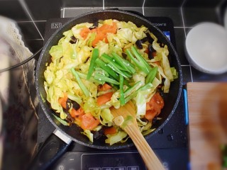 番茄炒包菜盖浇饭,炒至包菜断生(八分熟)时，加入青椒，再加入适量的生抽，继续翻炒。