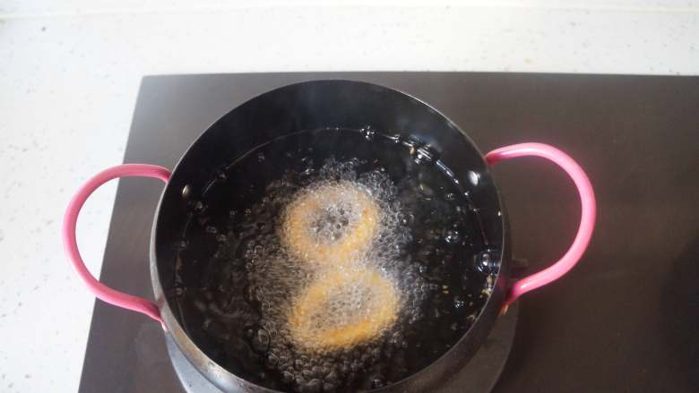 香酥鱿鱼圈,锅中倒油烧到5成热，放入处理好的鱿鱼圈，中火炸定型，再转小火炸到金黄色即可。