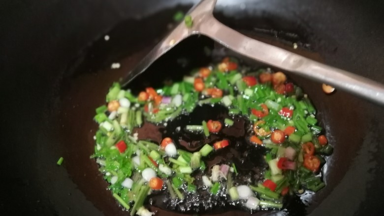 酱拌折耳根,锅中放适量油，油微热时倒入葱白、香菜茎和小米椒，改小火。
