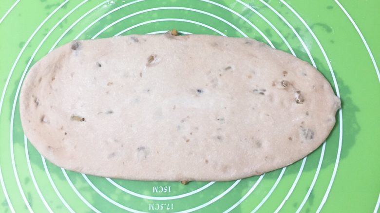 奶酪核桃面包,面团整理后盖上保鲜膜静置20分钟，再将面团擀成椭圆形。