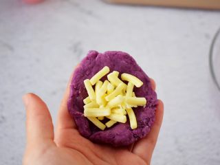 紫薯芝士球,我把面团分成8份，一份大约30克，把面团揉圆按扁，再放入芝士碎
