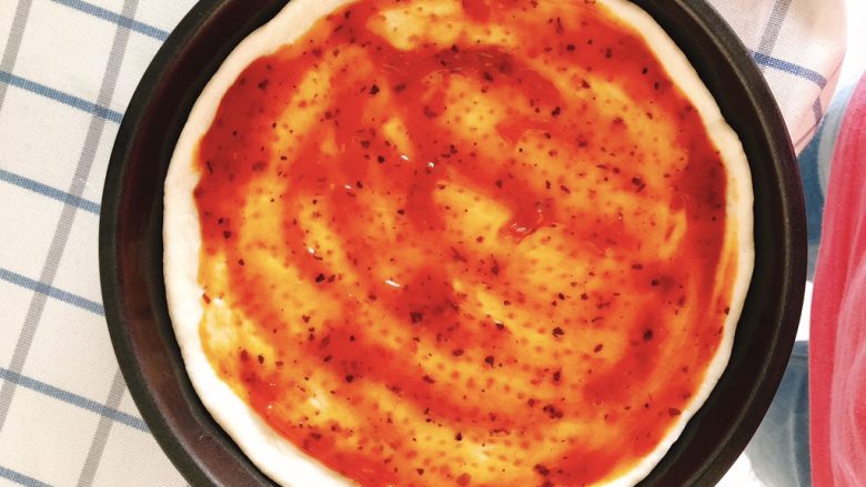 芝士培根披萨,涂上一层批萨酱。