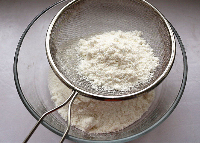 红豆蒸松糕,将搓散的面团过筛，可以借助小勺轻轻按压。过筛可以使米粉均匀，蒸出来的米糕才会松松软软。