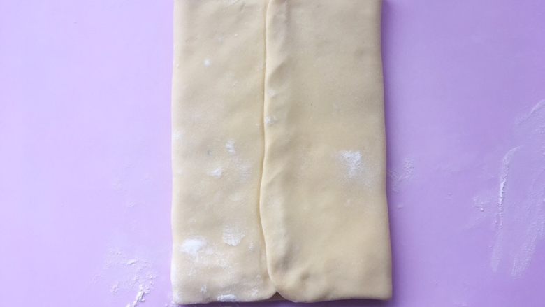 可颂热狗,将两侧的面片向中间对折，包裹上黄油片，封口处捏紧。