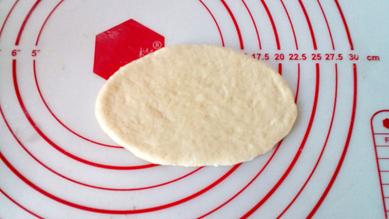 台式葱面包,取一个松弛好的面团，擀成椭圆形。
