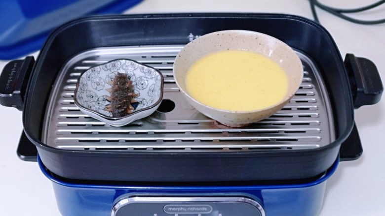 营养早餐 海参蒸蛋羹,美食锅中加入水，放入蒸屉，将蛋液碗与海参碟子放在蒸屉上。(一定将蛋液碗盖上盖子，或者包上耐高温的保鲜膜也可以)