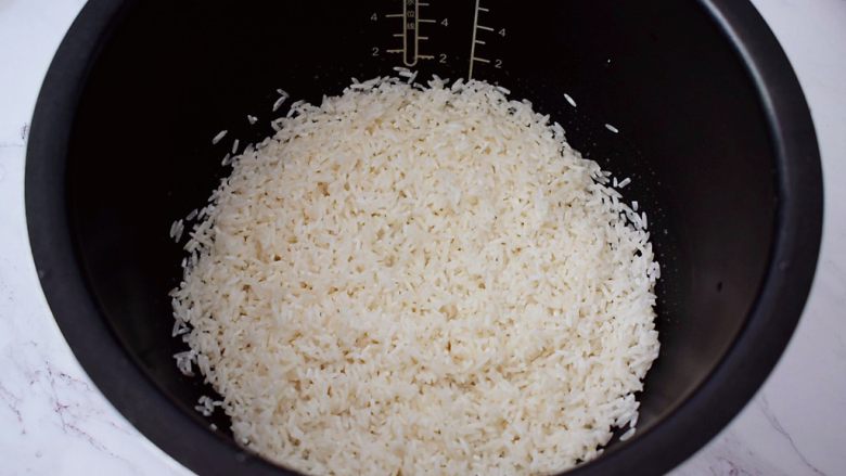 土豆腊肠焖饭,把淘洗干净的大米放入电饭煲内胆中