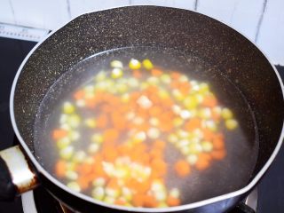 杂蔬火腿肠披萨,锅中烧开水，放入胡萝卜粒和玉米粒焯熟后