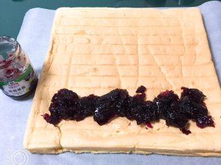 蓝莓蛋糕卷,用一张烤盘纸垫上，蛋糕放在纸上，蓝莓果酱铺上。