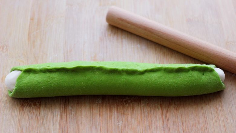 翡翠白玉生煎包,然后把绿色面皮包住白色长条，把边边用手捏紧。