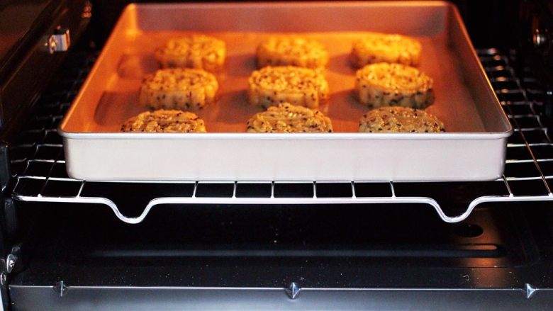 酥得掉渣的芝麻桃酥,把烤架放入烤箱中层，把做好的桃酥烤盘放烤网上。