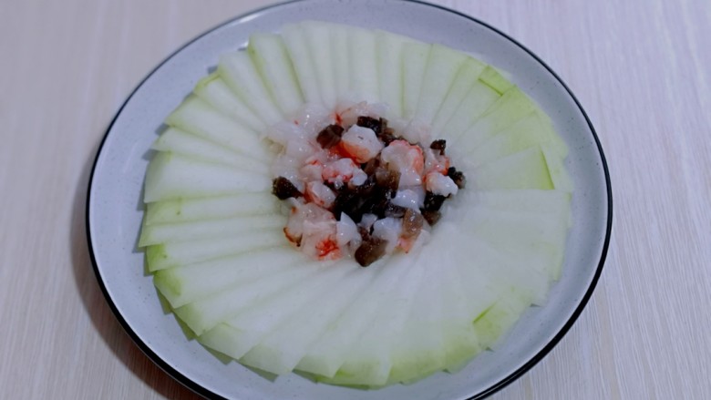 虾蓉蒸冬瓜,将腌制好的虾蓉及海参放在冬瓜盘的中间，如图。