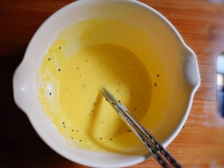 紫薯糯米鸡蛋卷,将炒熟的黑芝麻倒入鸡蛋液中，搅拌均匀。