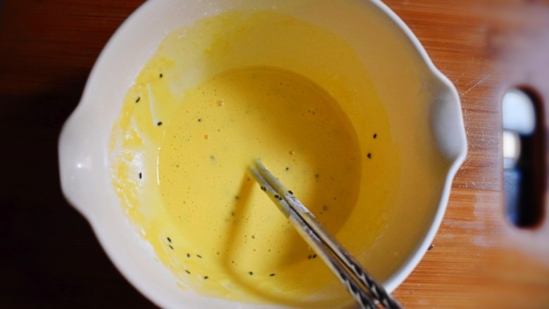 紫薯糯米鸡蛋卷,将炒熟的黑芝麻倒入鸡蛋液中，搅拌均匀。
