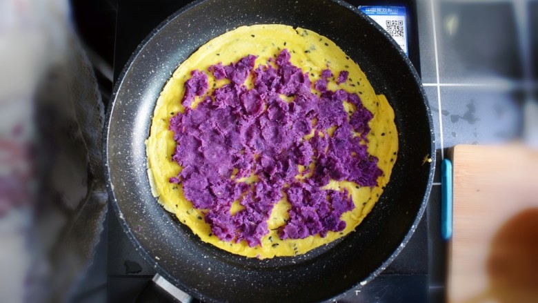 紫薯糯米鸡蛋卷,将紫薯泥平铺在煎好的鸡蛋糯米饼上。