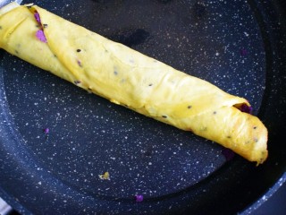 紫薯糯米鸡蛋卷,将鸡蛋饼卷起，同时在封口处抹上碗中剩余的鸡蛋糯米粉糊的残留，将口封住。