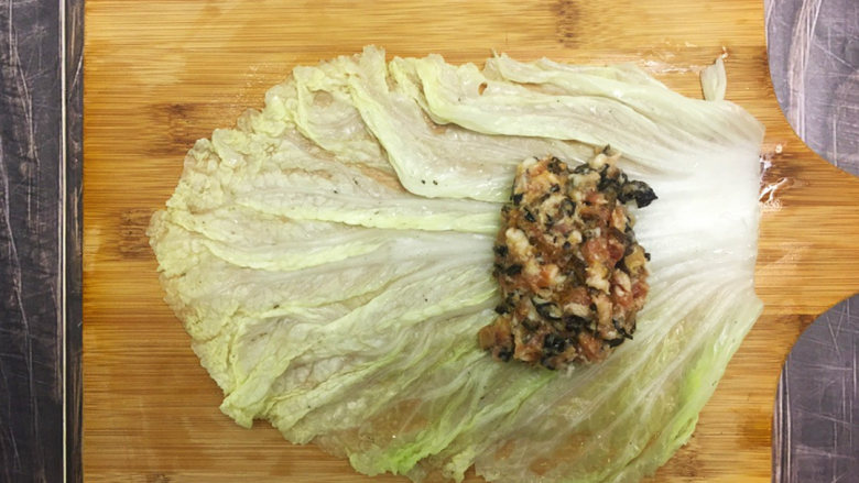 金玉白菜卷,将白菜叶铺平，放上肉馅，两边的菜叶往肉馅包上，再从下往上卷起