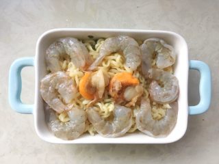 海鲜焗面,烤箱预热180度，用筷子夹出腌制好的虾仁跟扇贝，均匀的摆放在焗盘内
