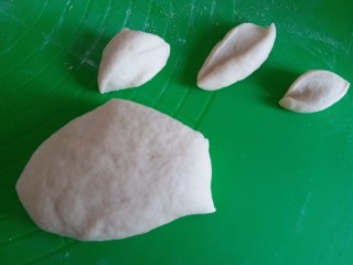 手撕肉松面包,发酵好的面团取出来用擀面杖排气，然后覆盖保鲜膜松弛30分钟，再用刮板把面团切小，我随意切的没有称重。