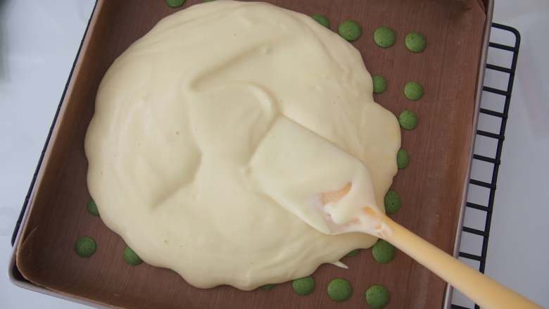 波点蛋糕卷,将原味面糊距离烤盘20厘米左右倒入；用刮刀将面糊铺平，震出大气泡