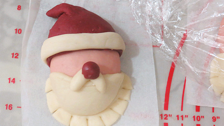 圣诞季滴中式点心【圣诞老人馒头】,把红色半圆形面片粘在粉红色面团上方，整理成帽子形，依次全部做完