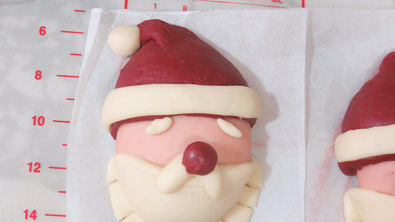 圣诞季滴中式点心【圣诞老人馒头】,揪预留的白色面团做出眉毛和帽子顶端的小白球，粘在相应的位置上，依次全部做完