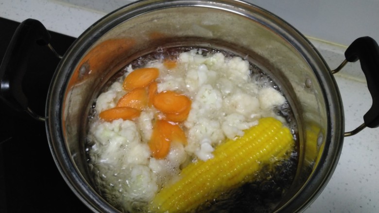 豆腐炒菜花,锅中放入适量水，水开后放入菜花焯水1分钟，放入胡萝卜焯水30秒，捞出。