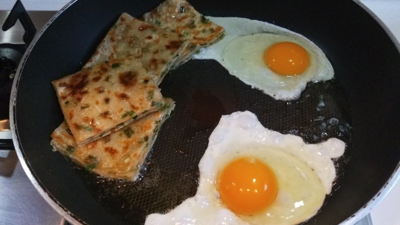 新文美食  葱油饼沾鸡蛋加肠片,用筷子把蛋黄挑开，撒上少许盐。