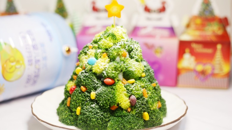 【圣诞美食】西兰花土豆泥圣诞树,将玉米、彩虹糖、胡萝卜碎不规则地嵌入西兰花中。顶部放一个切好的胡萝卜。从顶部均匀撒下一些奶粉，营造下雪的气氛。

