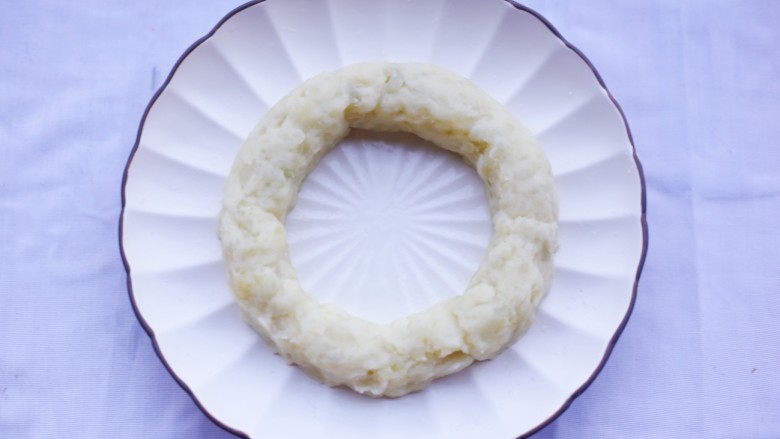 西兰花土豆泥版的圣诞花环,将处理好的土豆揉成圆环铺在盘上。