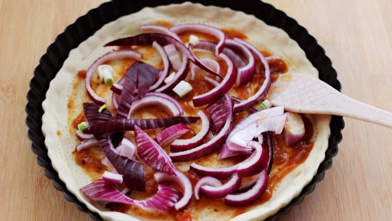 培根青豆披萨,加入提前切好的洋葱片，均匀地铺在披萨皮上面。