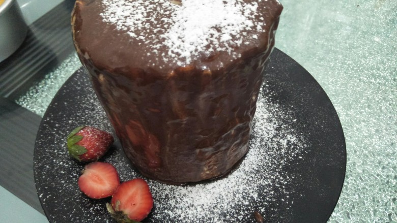巧克力蛋糕,放上水果在碟上洒上糖粉，插上装饰牌。