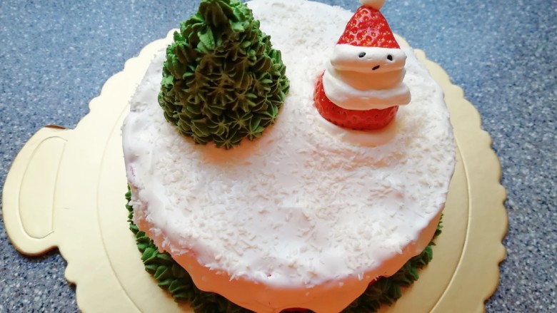 圣诞奶油蛋糕,将另外一颗草莓做一个圣诞老人放在蛋糕的另一边。具体做法是：草莓底部削平，从三分之二处切开，下半部分固定在蛋糕的另一边，做圣诞老人的身体，中间挤上白色的奶油，做圣诞老人的脸部，上半部分放在奶油上做圣诞老人的帽子，用黑芝麻做圣诞老人的眼睛和嘴。