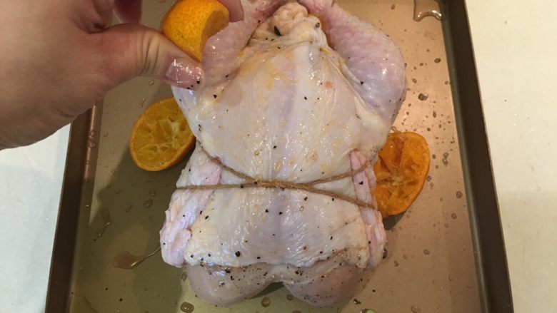 砂糖橘风味烤鸡,然后鸡胸朝上，将剩余的砂糖橘挤汁淋在鸡身上