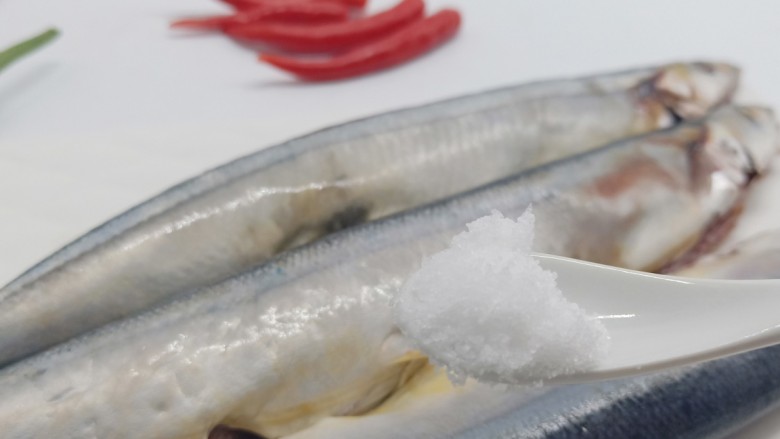 简单美味的麻辣烤秋刀鱼,加盐一勺，均匀地涂抹在鱼身上。