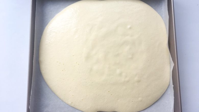 依云米奇蛋糕卷,将翻拌均匀的面糊抬高20厘米倒入烤盘内
