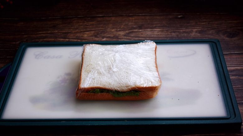 三明治,用保鲜膜包好。
用保鲜膜包裹之前用手将三明治压一压，压的扁些更便于包裹，用保鲜膜包裹时尽量包的紧实些。

