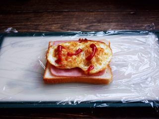 三明治,放入煎好的鸡蛋，挤上少许的番茄沙司。