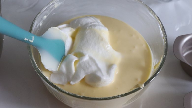 轻乳酪蛋糕（芝士蛋糕），醇香美味,取约1/3的蛋白，和蛋黄糊翻拌均匀，再倒入到蛋白盆中，继续翻拌均匀。