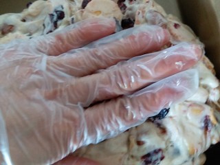 网红雪花酥,稍微冷却后，手上戴手套，两只手拿着糖团不断外翻，使每块饼干都均匀的裹上糖再放入不沾烤盘内，用手按平