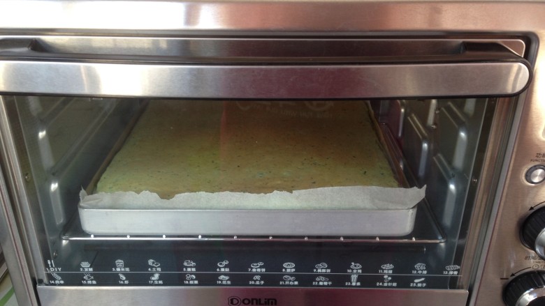 菠菜小蛋糕,将拌好的蛋糕糊倒入铺了油纸的烤盘里，在桌面上震出气泡，放入提前预热到180度的烤箱烘烤18分钟左右