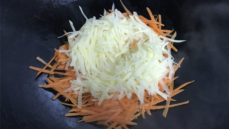 青椒胡萝卜炒土豆丝,7成热，先把胡萝卜丝放入锅中，然后把土豆丝一起放入。