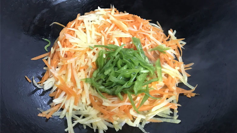 青椒胡萝卜炒土豆丝,把它们快速翻炒均匀后把青椒丝也一起放入。